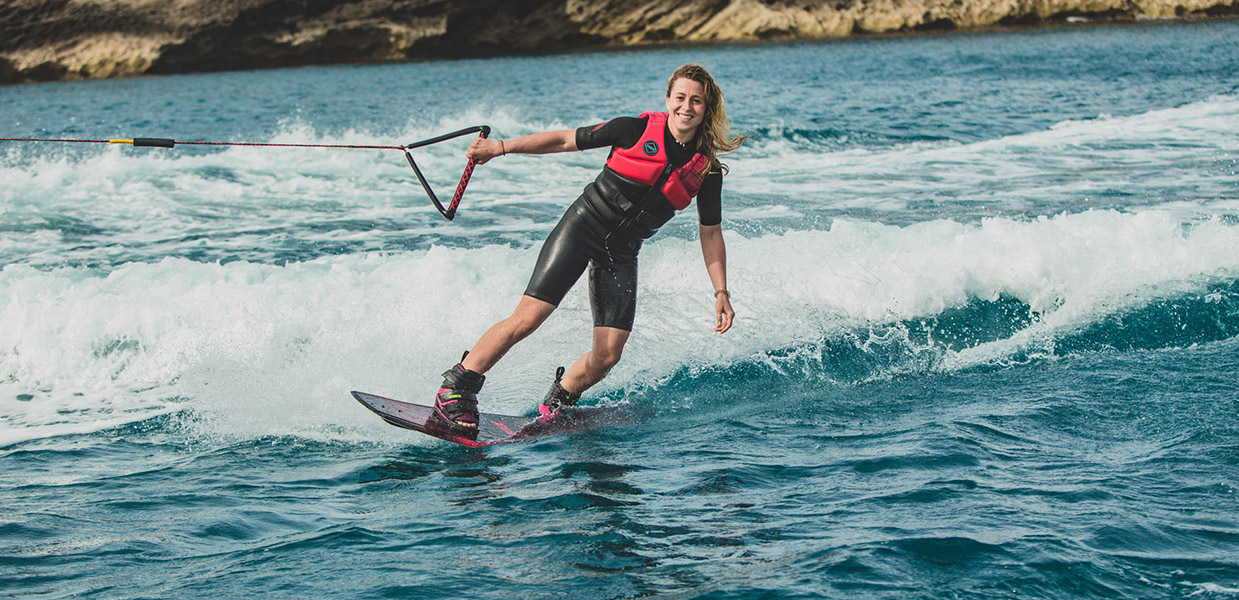Girl in a wetsuit enjoying wakeboarding on the sea.